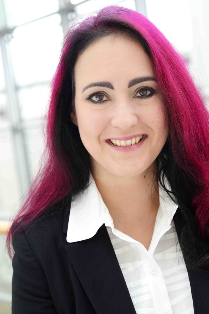 Violet-black and long haired female physicist in a business casual dress.